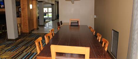 A conference room with a long table and chairs, carpeted floor, and a large window in the background.