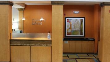 A reception area with a wooden reception desk, a sign reading "Connect & Print", and a framed abstract painting on the wall.