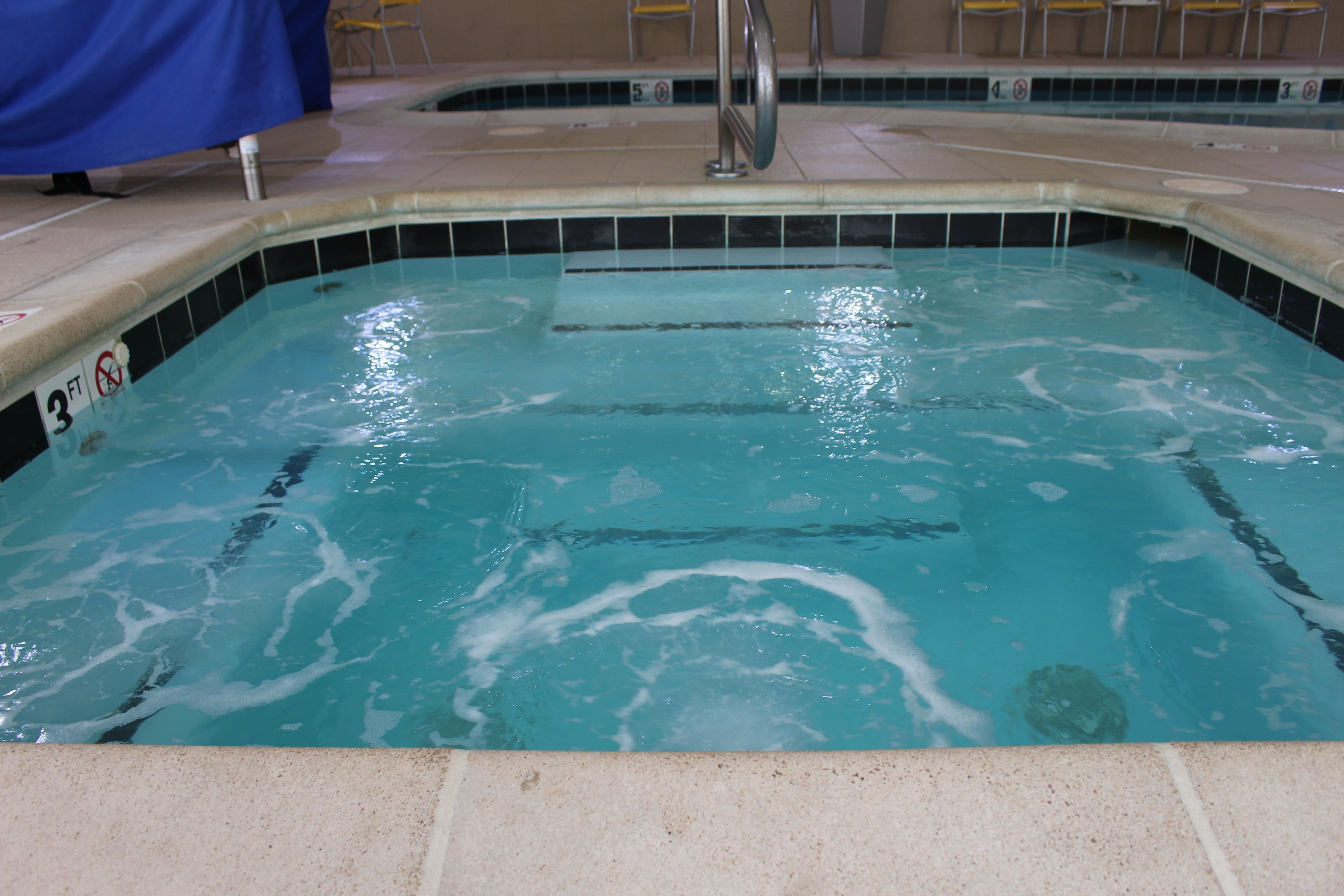 A swimming pool with a tiled edge, a metal handrail, and a '3 FT' depth marker.