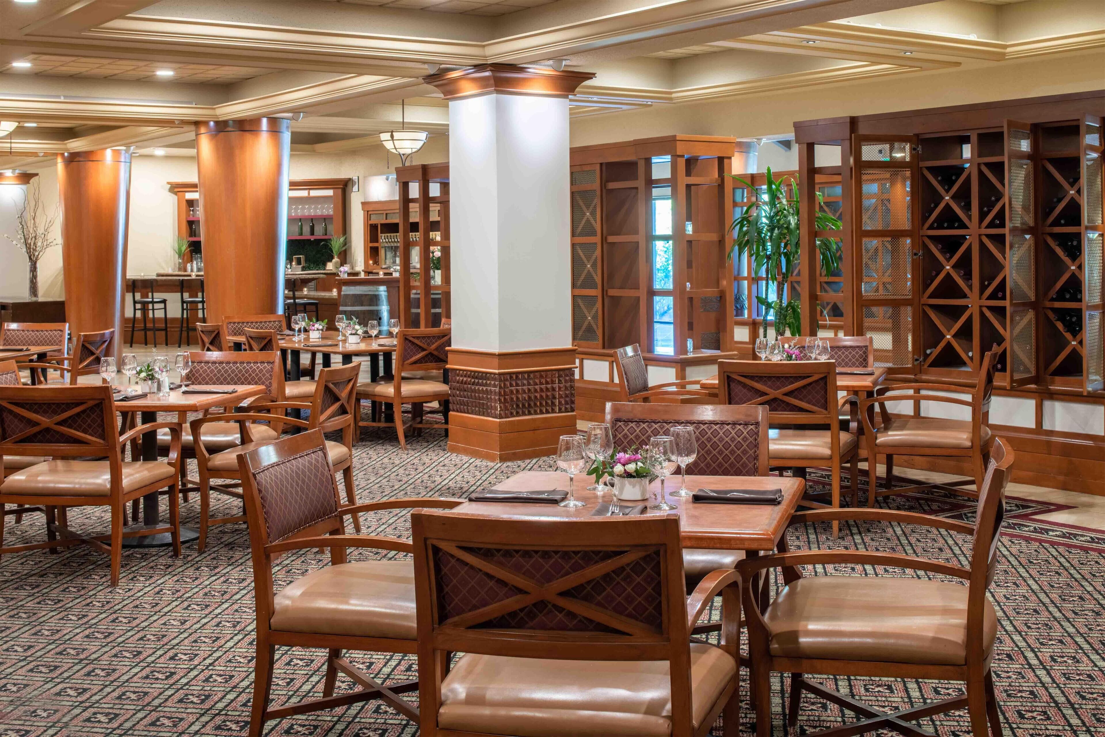 A restaurant with wooden furniture, tables, and chairs arranged for dining.