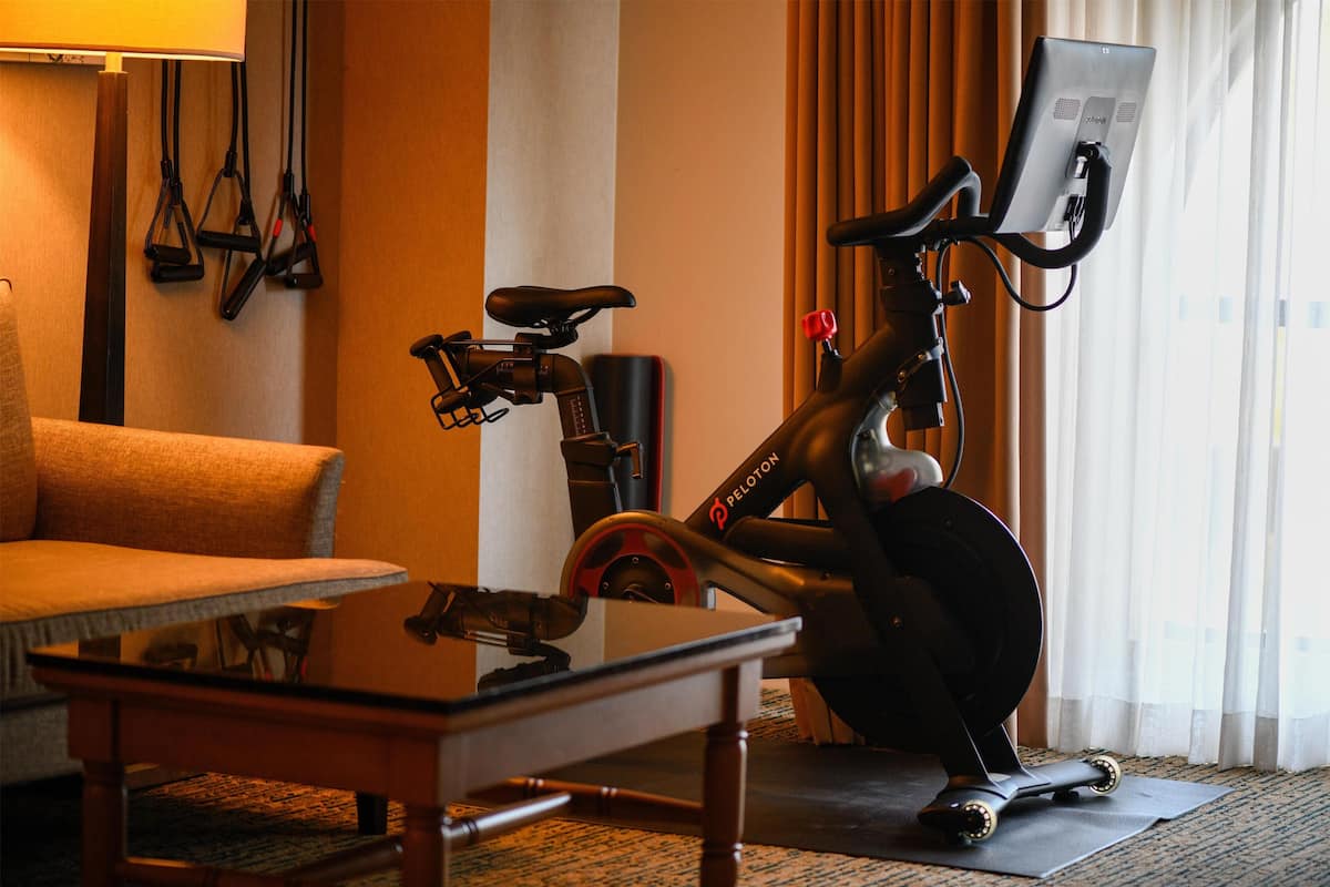 Une pièce comprenant un vélo d’appartement, un canapé et une table.