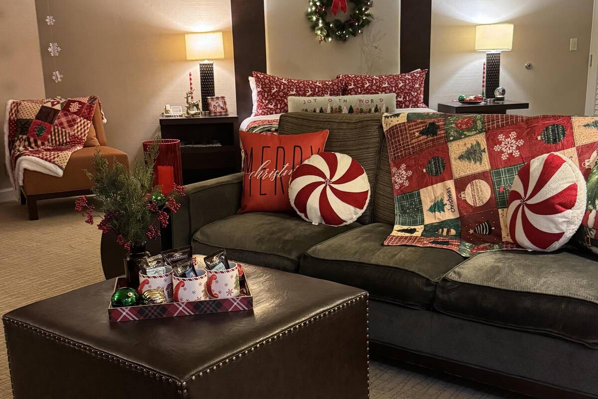 Un salon chaleureux avec un canapé en cuir, une table basse ornée d’un plateau décoratif sur le thème de Noël et une cheminée agrémentée d’un manteau décoratif.
