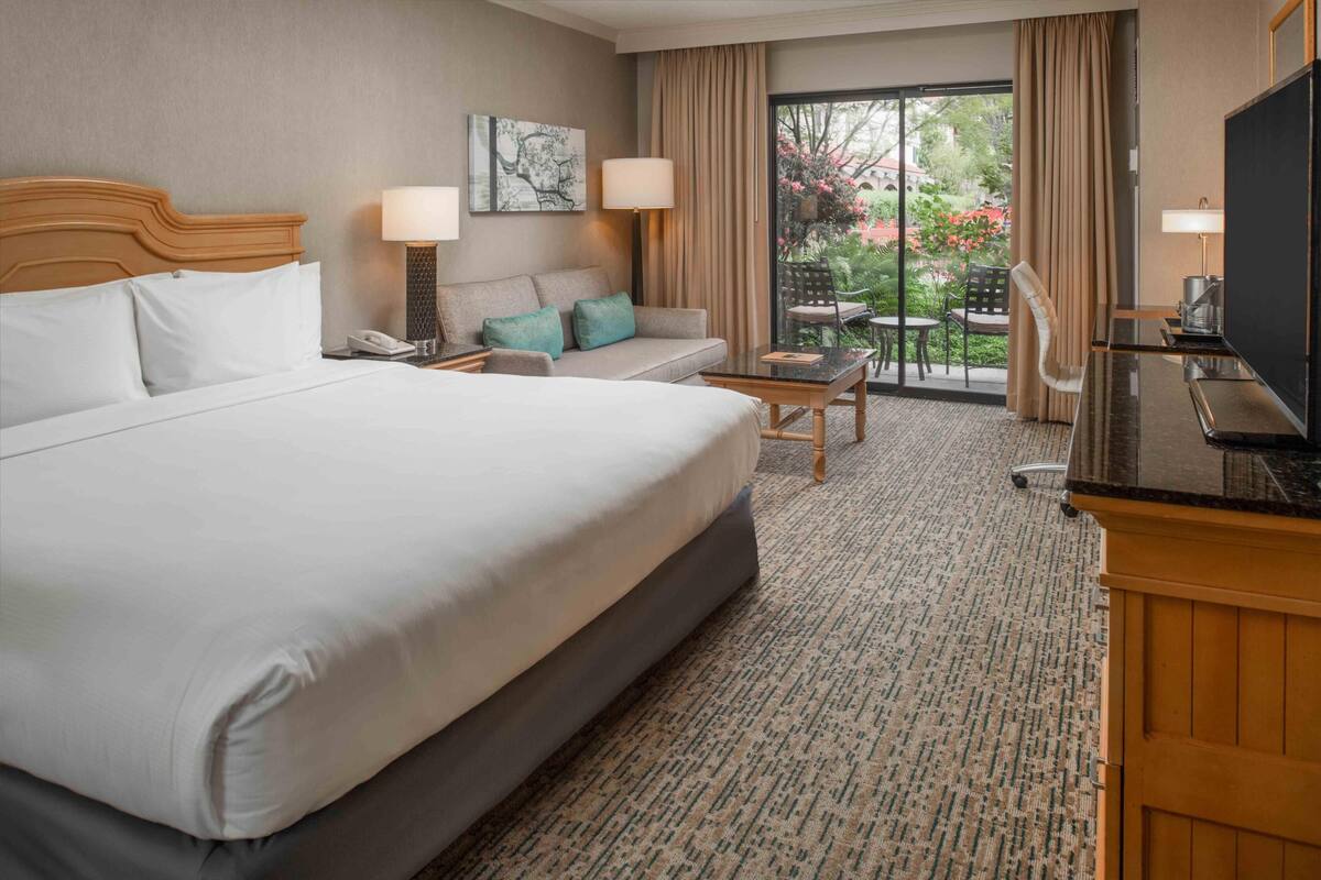 Une chambre d’hôtel avec un grand lit, un canapé, une petite table et un téléviseur.