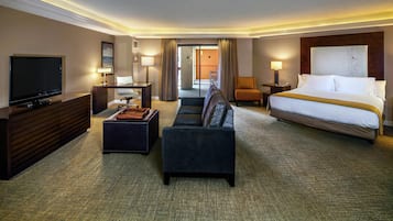 A hotel room with a bed, a TV, a sofa, a desk, and a chair.