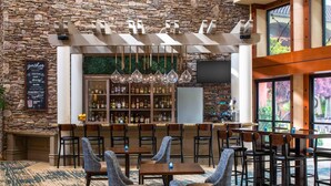 A restaurant with a stone wall, bar area, and seating arrangement. - DoubleTree by Hilton Sonoma - Wine Country (Rohnert Park)