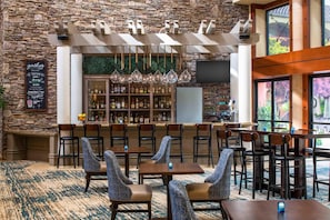 Un restaurante con pared de piedra, zona de bar y distribución de mesas.
