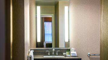 A hotel bathroom with a sink, mirror, and towel rack.