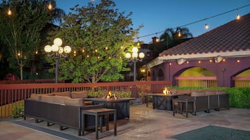An outdoor patio with seating, string lights, and a fire feature.