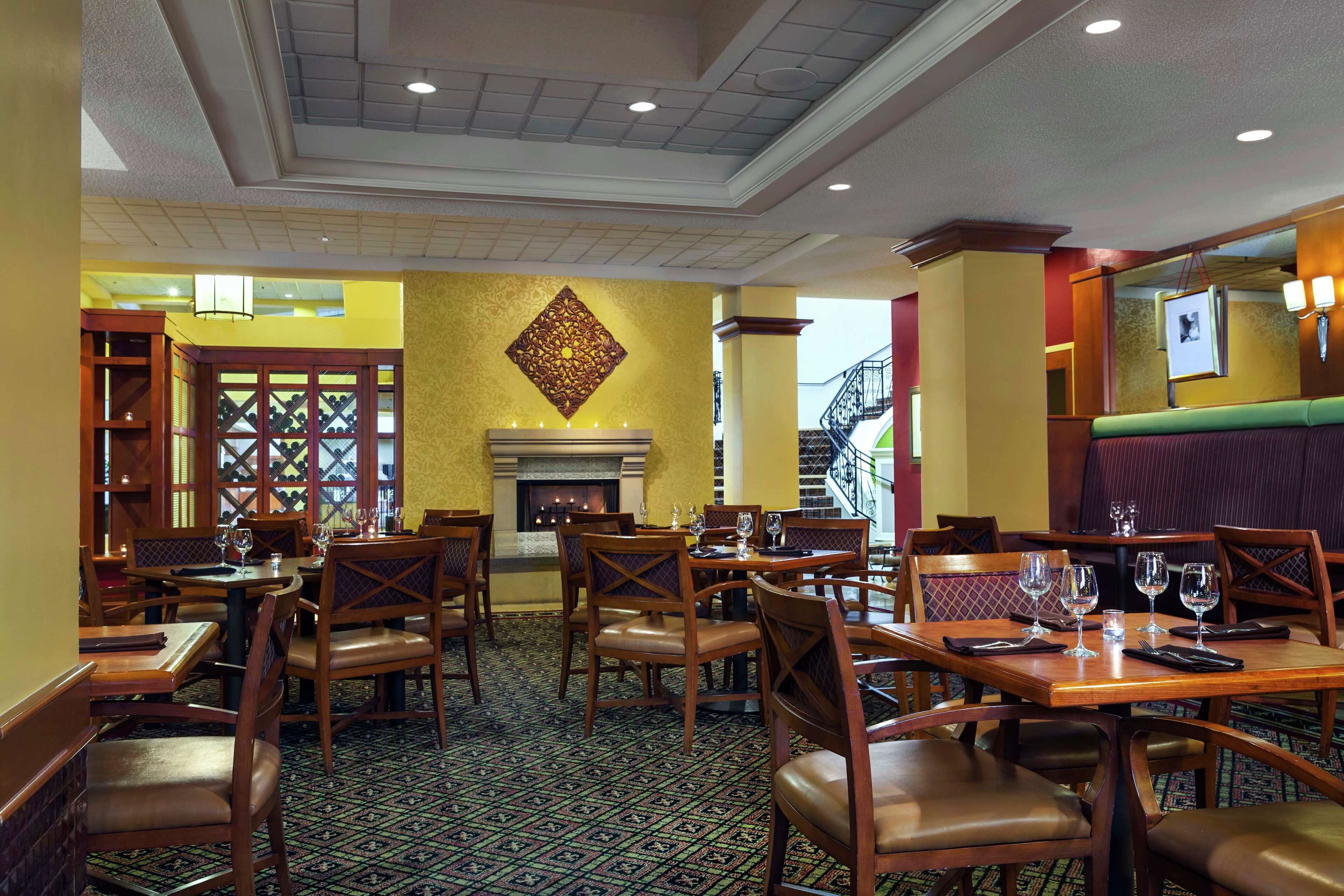 Un restaurant avec des tables et des chaises en bois, une moquette à motifs et une cheminée.