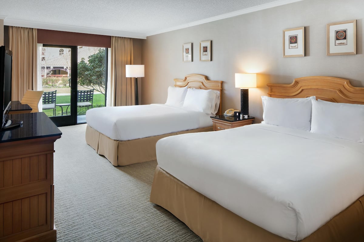 Une chambre d’hôtel avec deux lits, un bureau et une vue sur l’extérieur.