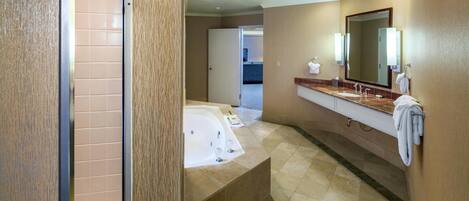 A modern bathroom with a large bathtub, a separate shower area, and a vanity with a mirror.
