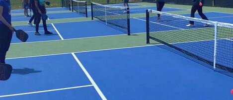 A tennis court with multiple players and a net.