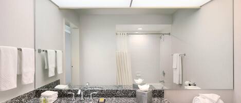 A modern bathroom with a granite countertop, a sink, a mirror, and a toilet.