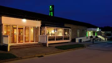 A building with a storefront, a staircase, and a green-lit tower.