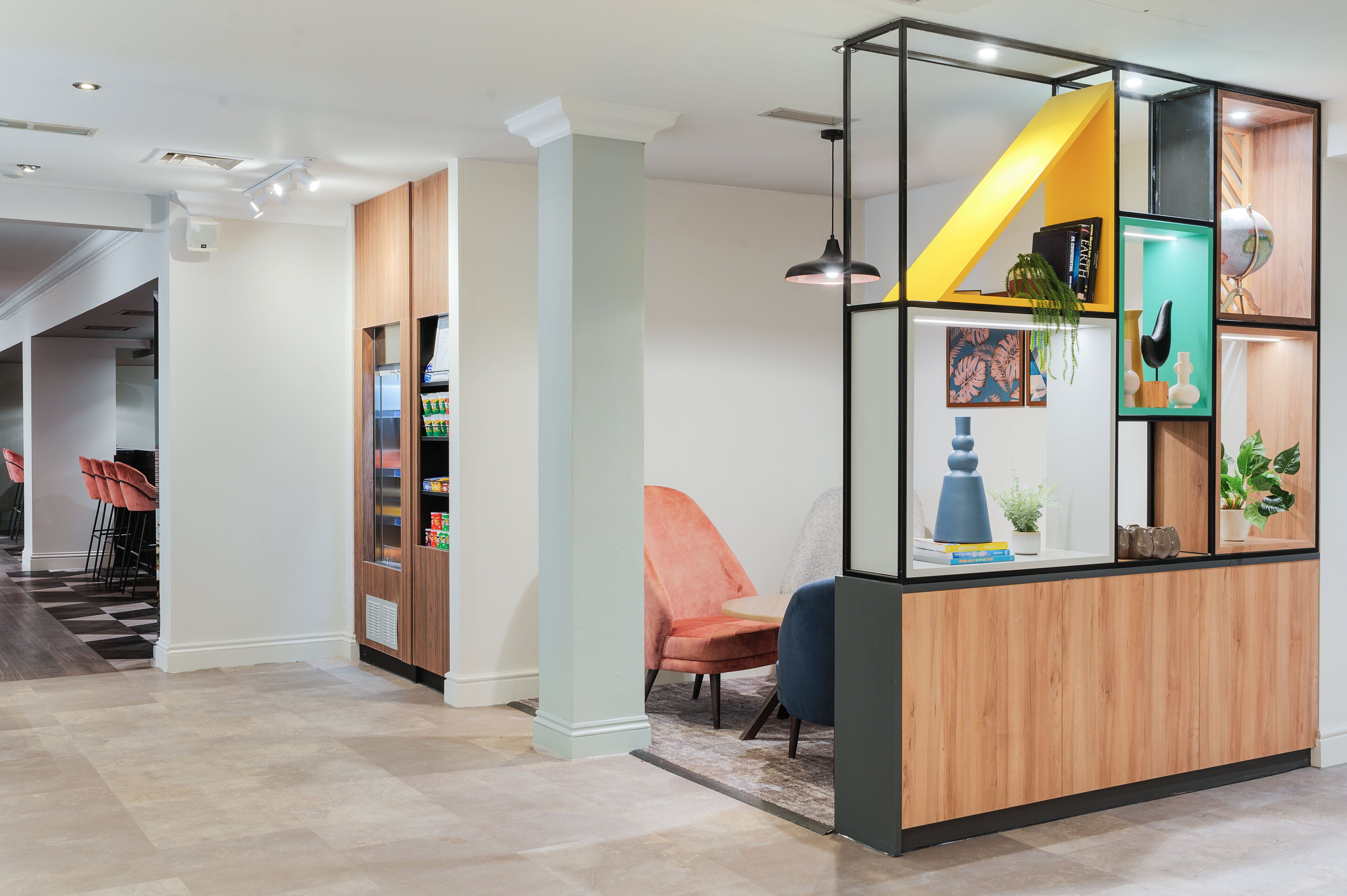 Un área de recepción moderna con un escritorio de madera, una silla azul y una pared de acento amarilla.