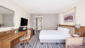 A hotel room with a bed, a desk with a chair, a television, and a painting on the wall. - Holiday Inn Derby Nottingham M1 J25 by IHG (Nottingham)