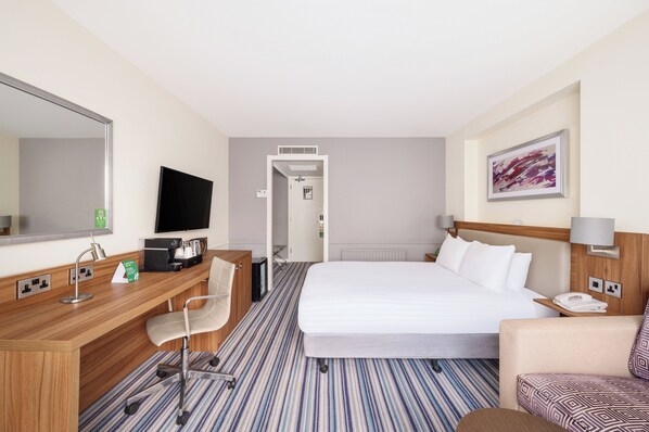 A hotel room with a bed, a desk with a chair, a television, and a painting on the wall. - Holiday Inn Derby Nottingham M1 J25 by IHG (Nottingham)