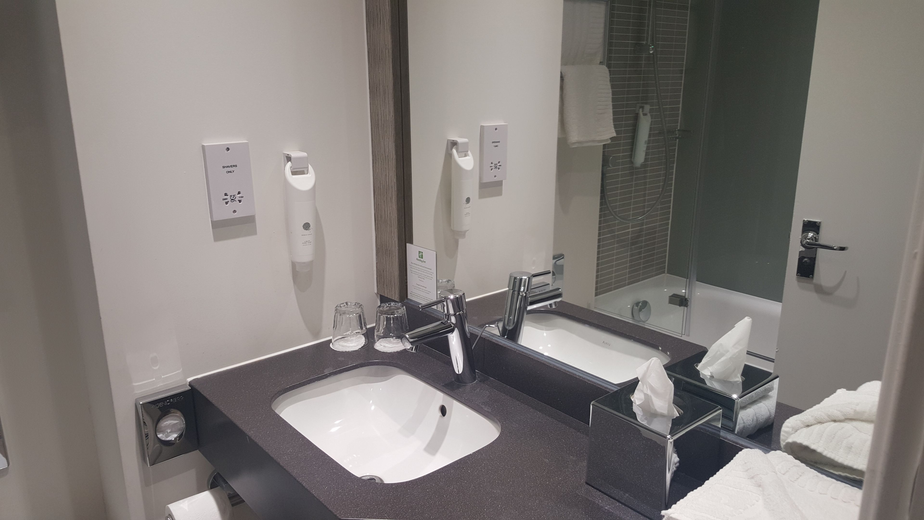 Ein modernes Badezimmer mit zwei Waschbecken, einem großen Spiegel und einer Duschkabine aus Glas.