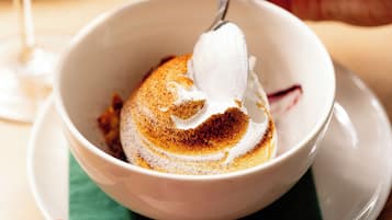 A white bowl with a dessert topped with whipped cream and a sprinkle of cinnamon.