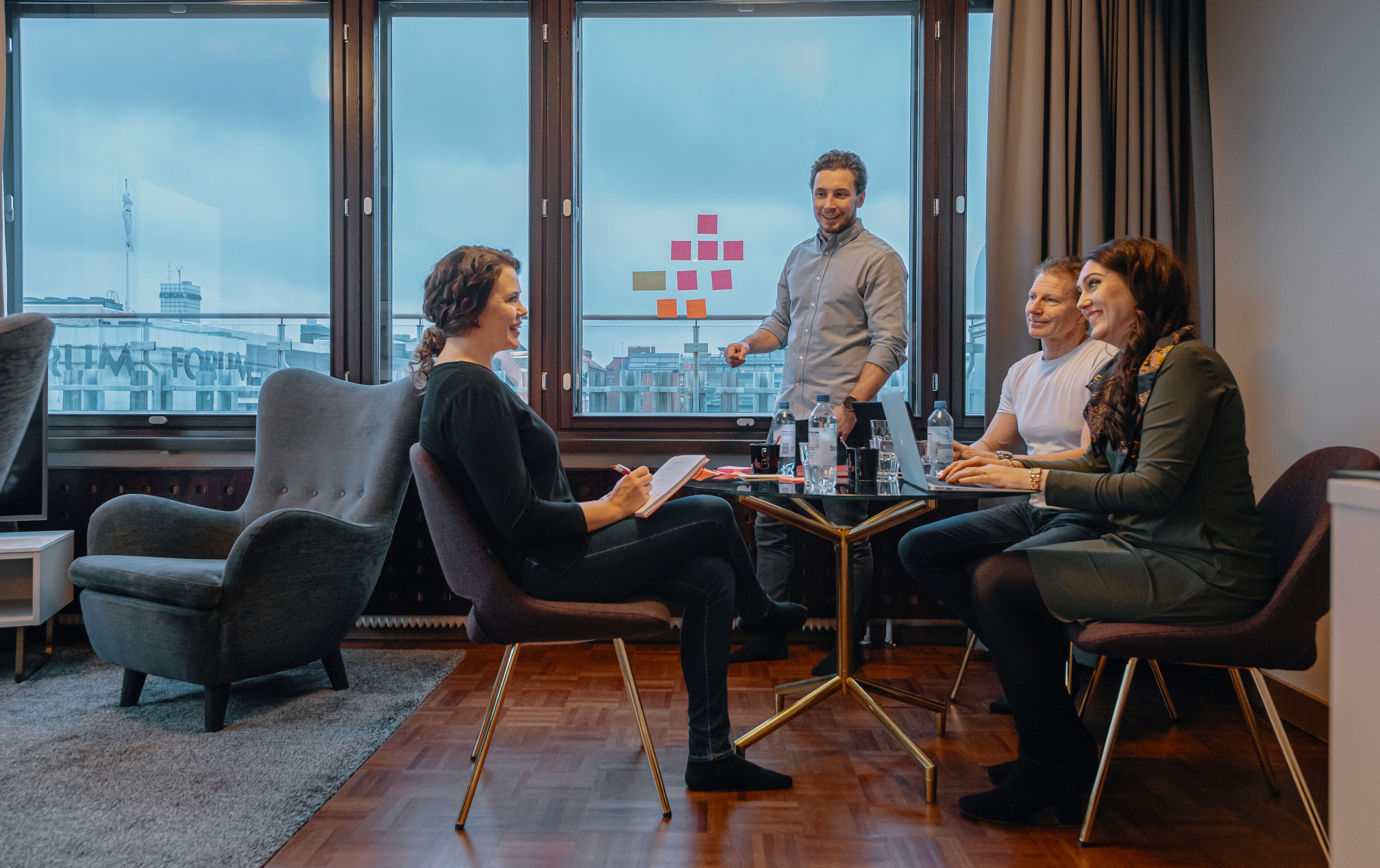A meeting room with a city view, modern chairs, a glass table, and a laptop.