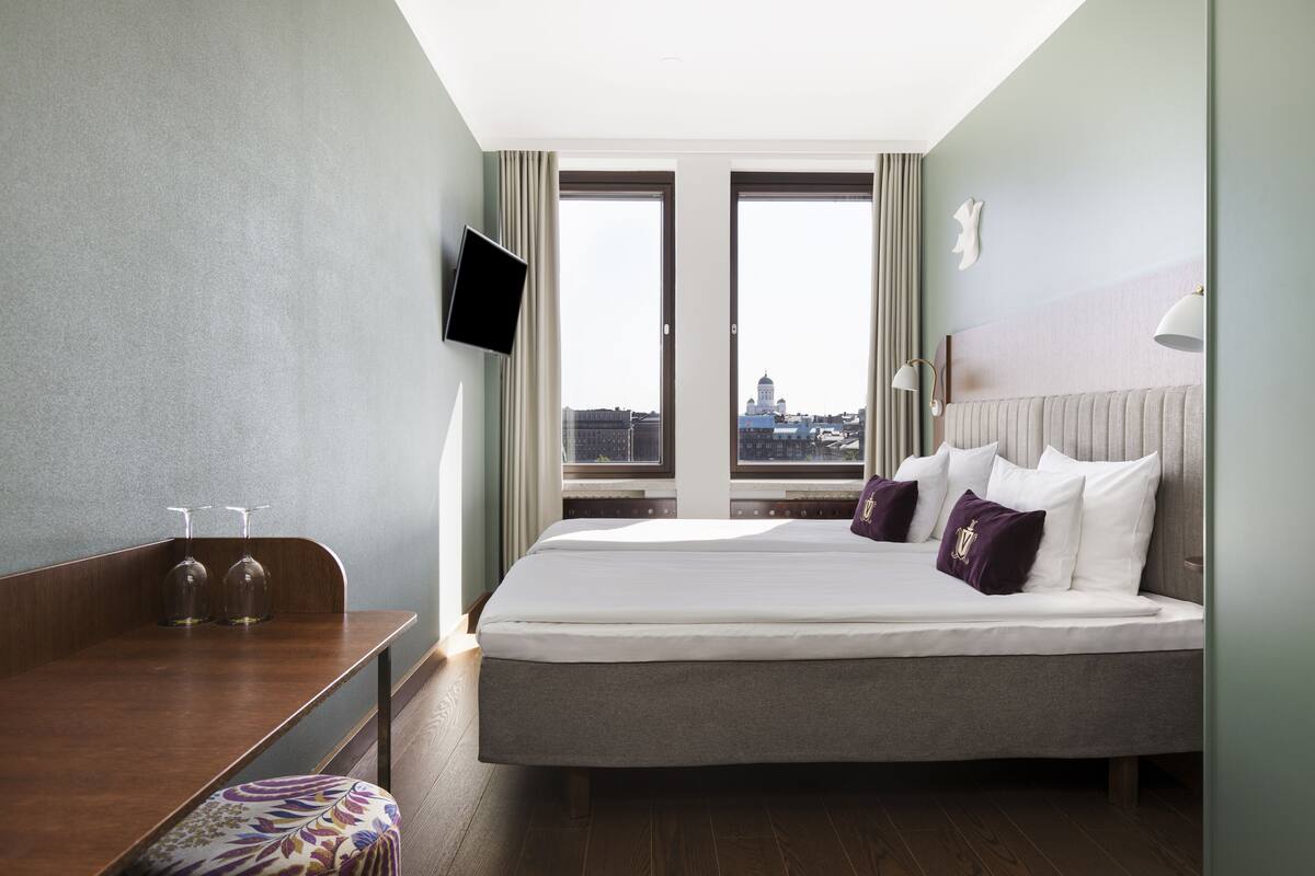 Habitación de hotel con cama, escritorio y televisión.
