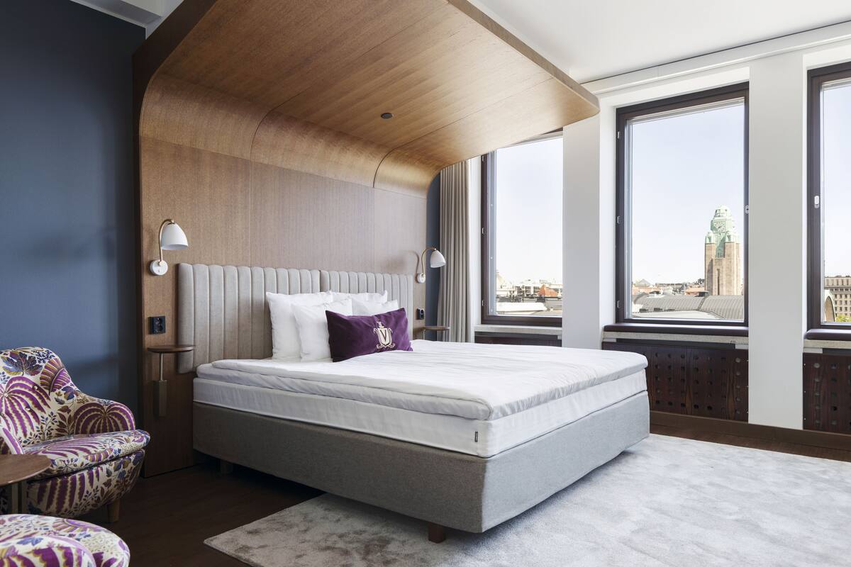 Un dormitorio moderno con una cama grande, vistas a un paisaje urbano y un diseño de techo original.