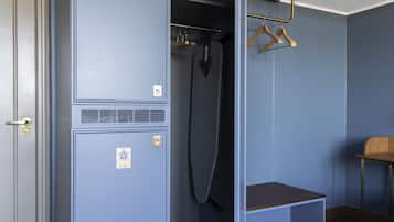 Una habitación con un armario, un planchador colgante y una silla de madera.