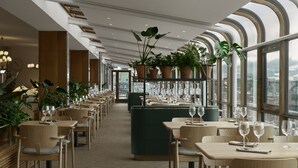 Un restaurante moderno con mesas largas, sillas y plantas en macetas.