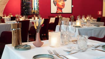 Un interior de restaurante con mesas dispuestas para comer, con velas, cristalería y una bodega en el fondo.