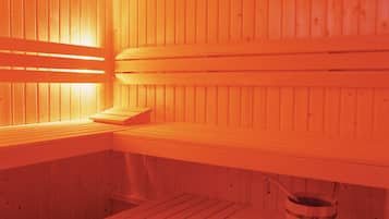 Una sauna amb seients de fusta i un cubell.
