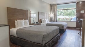 A hotel room with two beds, a desk, a chair, a lamp, and a large window with curtains. - Boca By the Sea (Boca Raton)