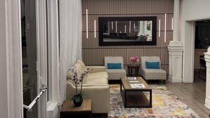 A modern living room with a sofa, armchairs, a coffee table, and a patterned rug. - Boca By the Sea (Boca Raton)