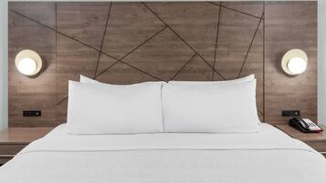Ein Hotelzimmer mit einem großen Bett, zwei Nachttischen und einem modernen Kopfteil mit geometrischen Mustern.