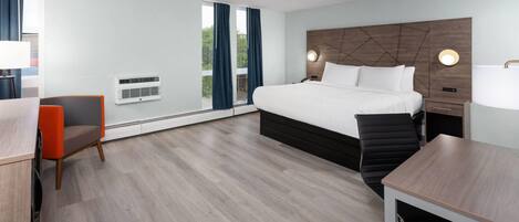 Ein modernes Hotelzimmer mit einem großen Bett, einem Schreibtisch, einem Stuhl und Blick ins Freie.
