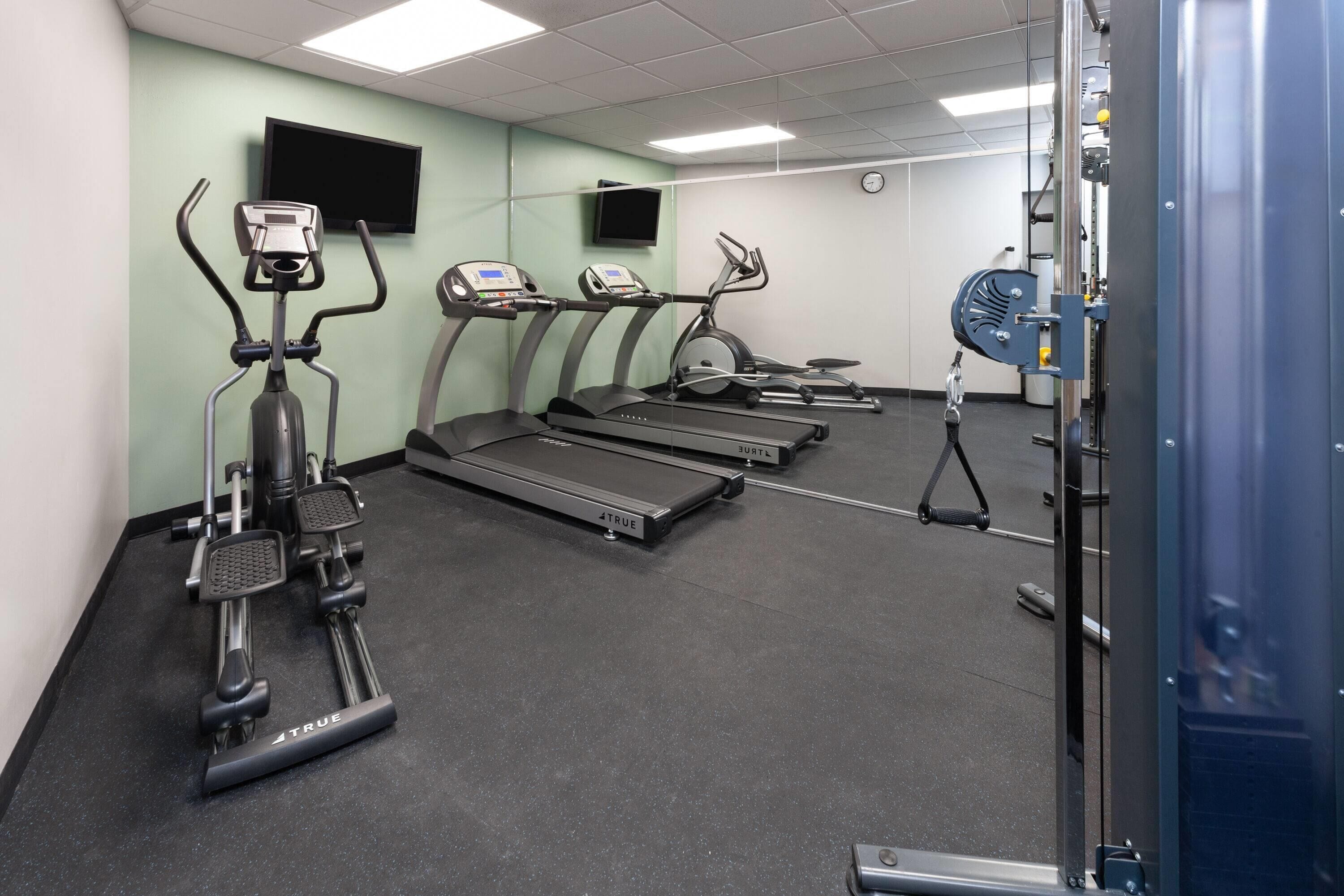 A gym with treadmills, elliptical machines, and a stationary bike.