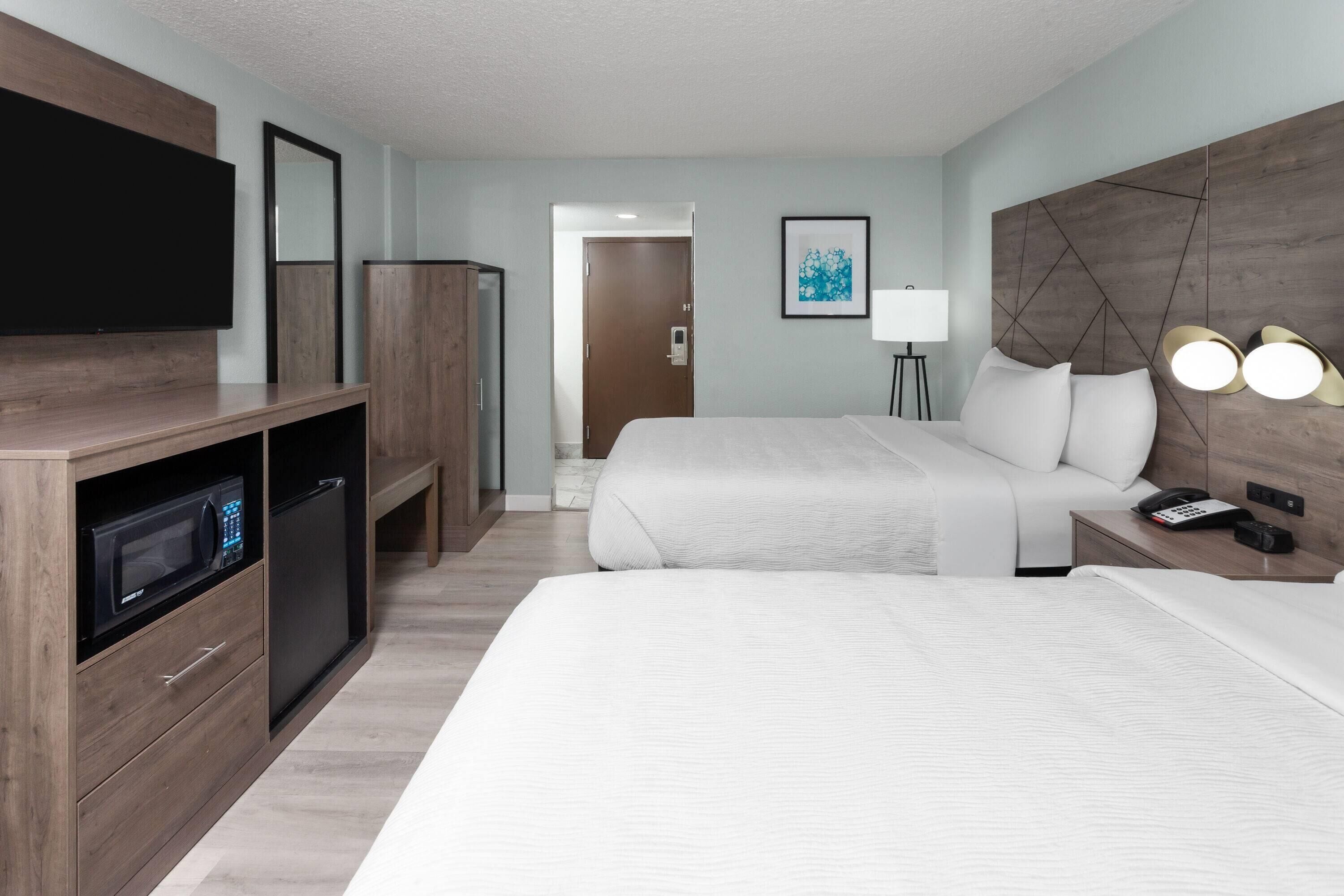 A hotel room with a large bed, a TV, a microwave, a desk, and a bedside lamp.