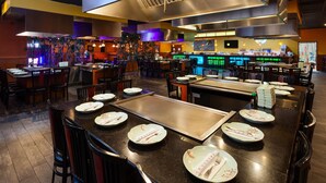 Um restaurante com v árias mesas, cadeiras e um bar.