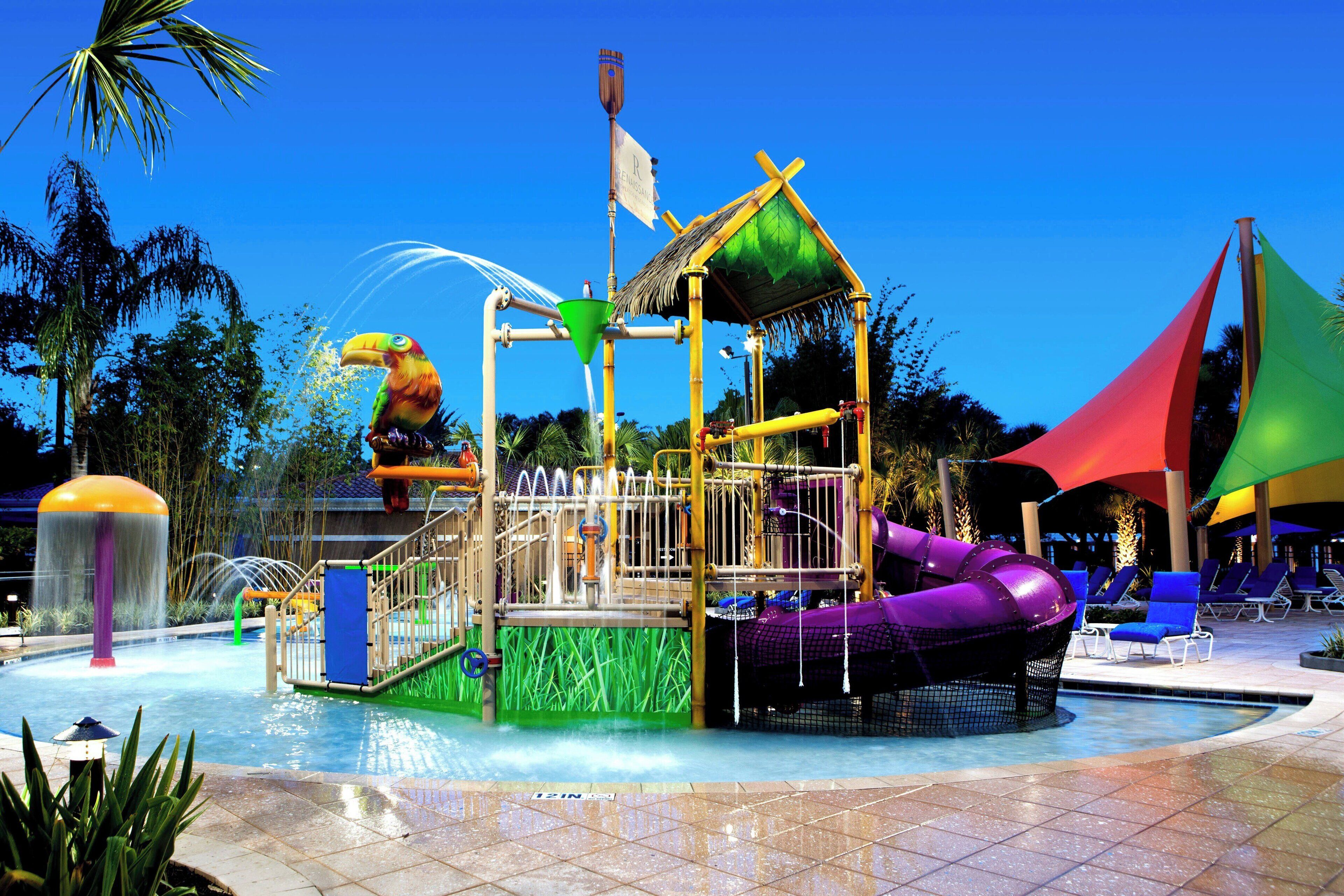 Ein Wasserpark mit Rutsche, Spielbereichen und Liegestühlen.