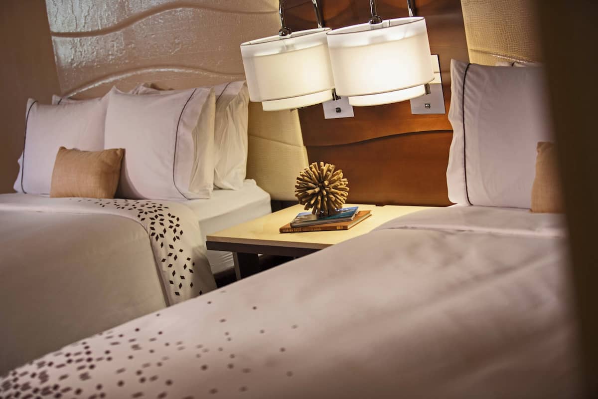 Een hotelkamer met twee bedden, een nachtkastje en een wandlamp.