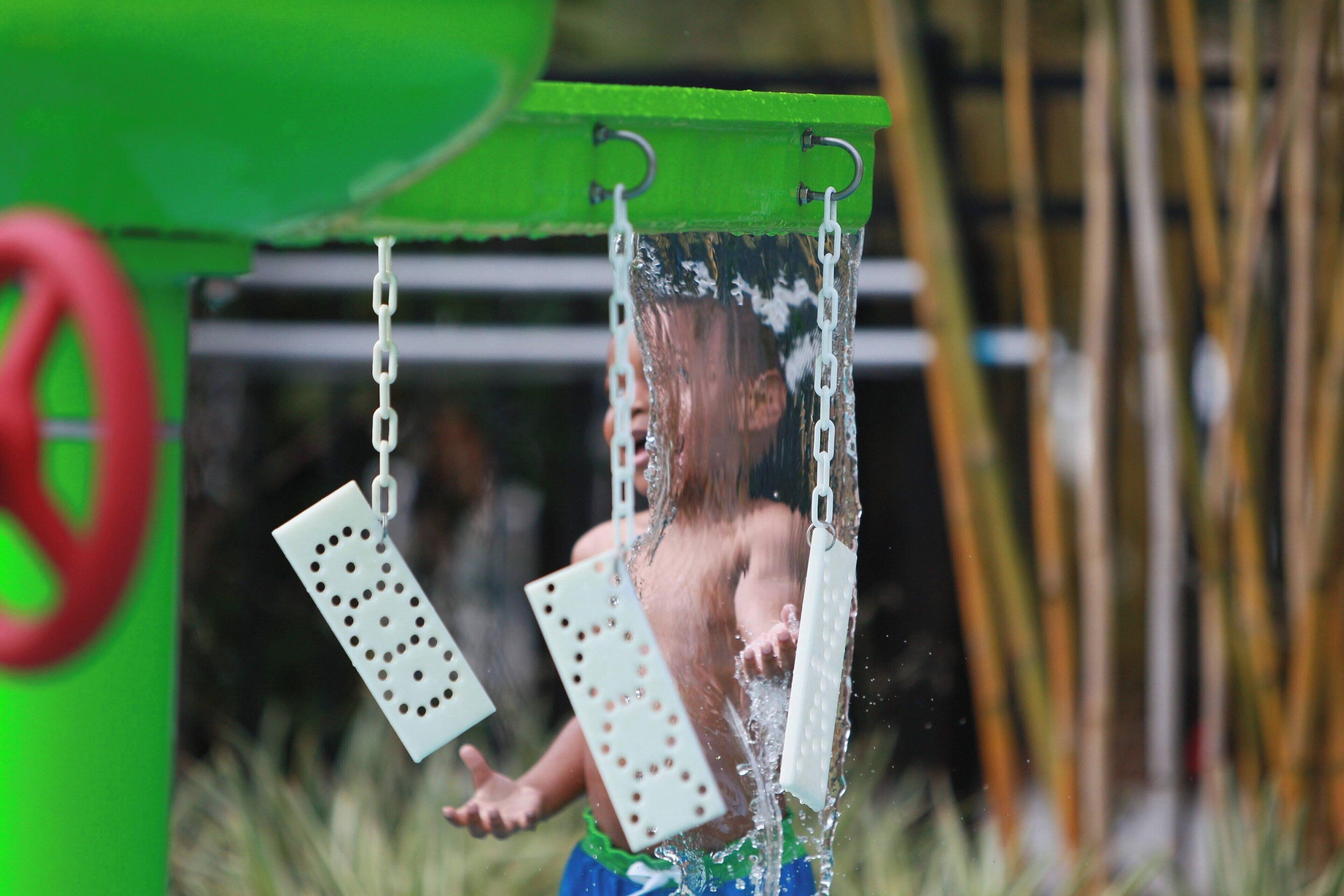 Un enfant se balance sur une balançoire munie d’une chaîne et d’une barre métallique.