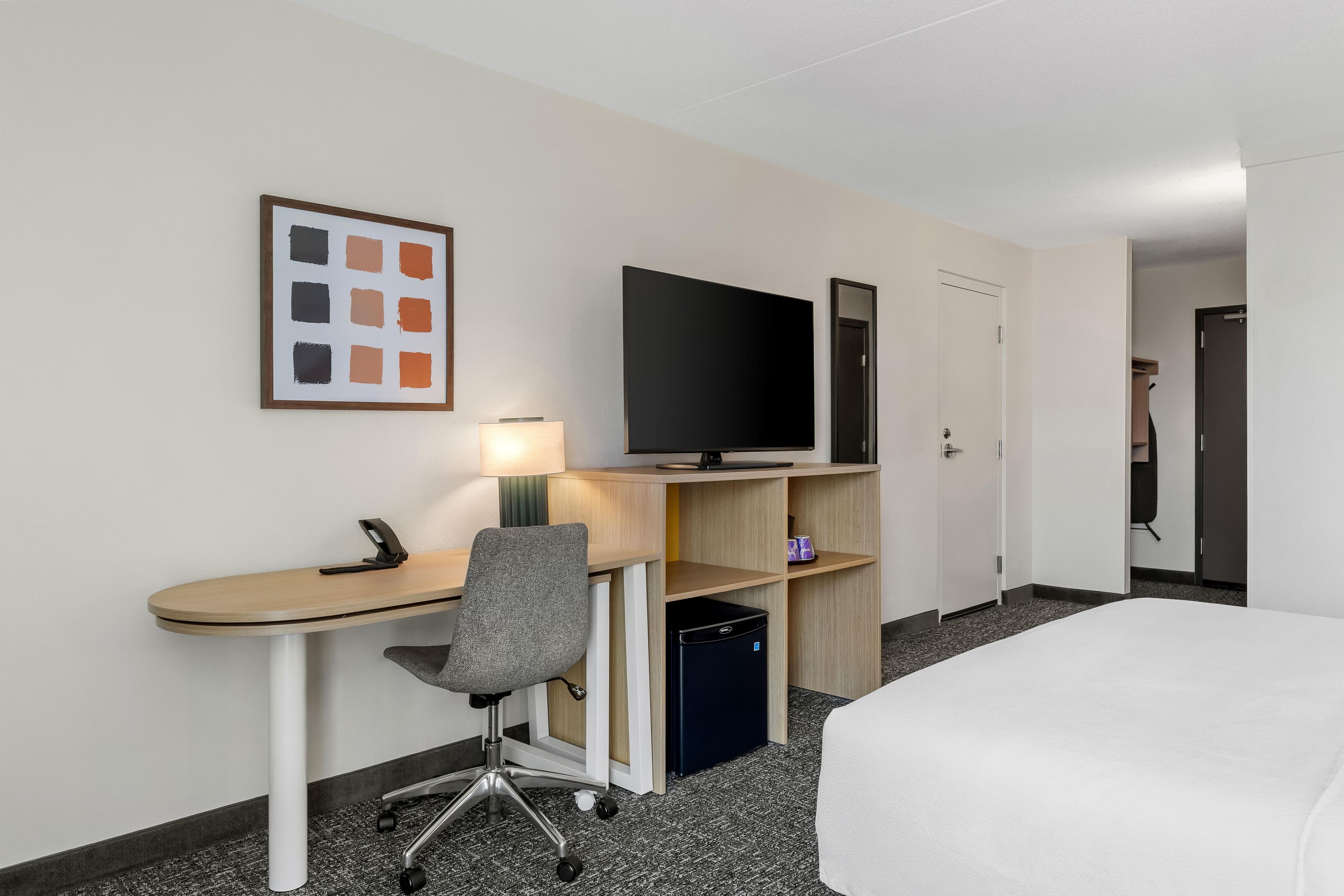Una habitación de hotel con escritorio, silla, televisión y cama.