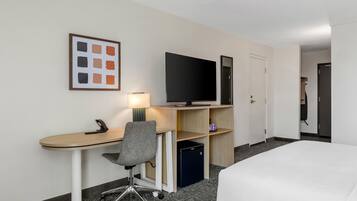 Una habitación de hotel con escritorio, silla, televisión y cama.