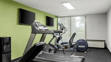 Un gimnasio con cintas de correr, elíptica y dispensador de agua.