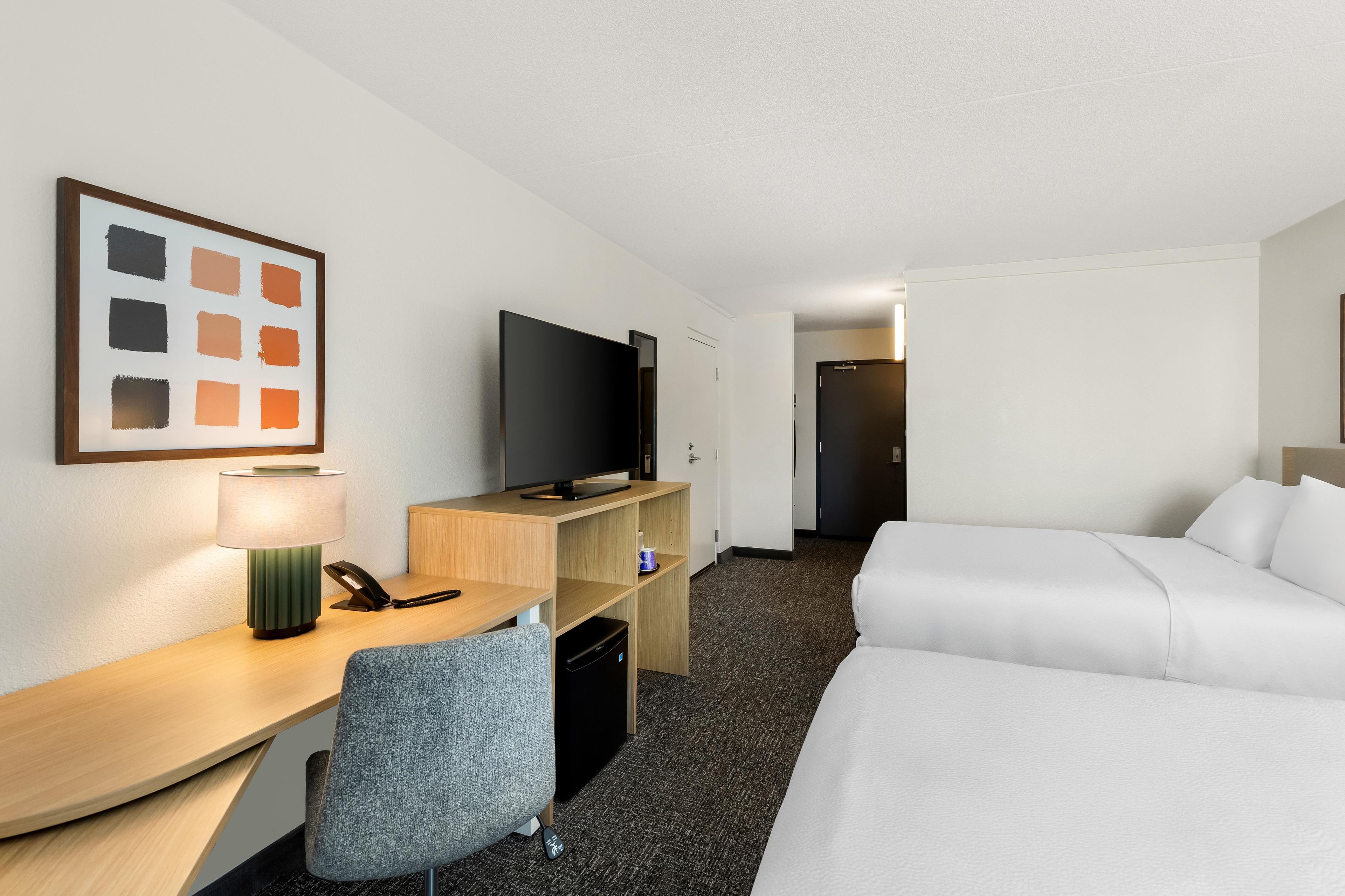 Ett hotellrum med ett skrivbord, en tv, en säng och en stol.