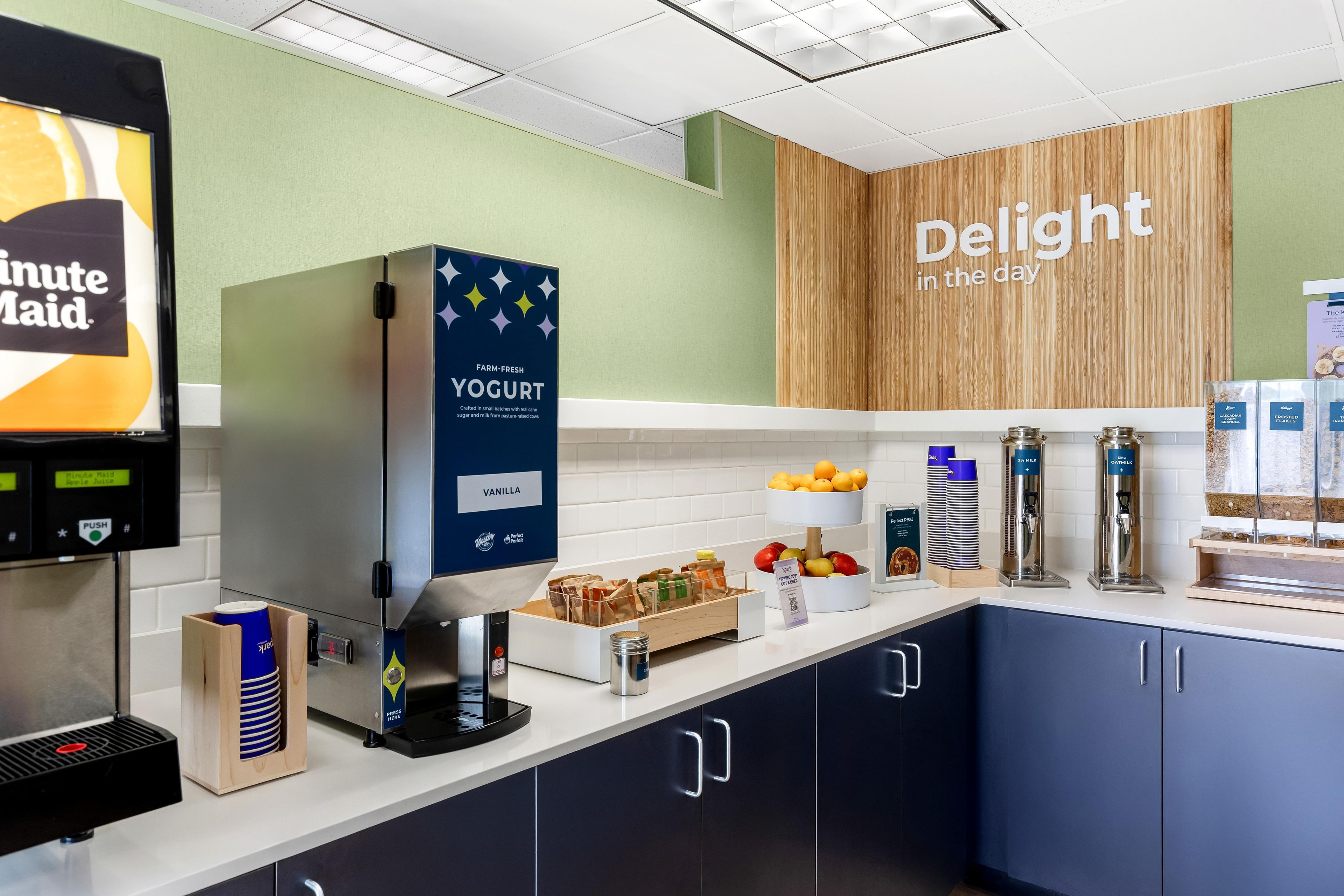 Een ontbijtbuffet met een yoghurtautomaat, een koffieapparaat en diverse soorten eten.