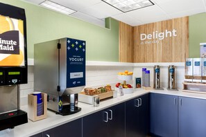 A self-service breakfast station with a yogurt dispenser, a coffee machine, and a variety of food items. - Spark by Hilton Akron Fairlawn (Akron)
