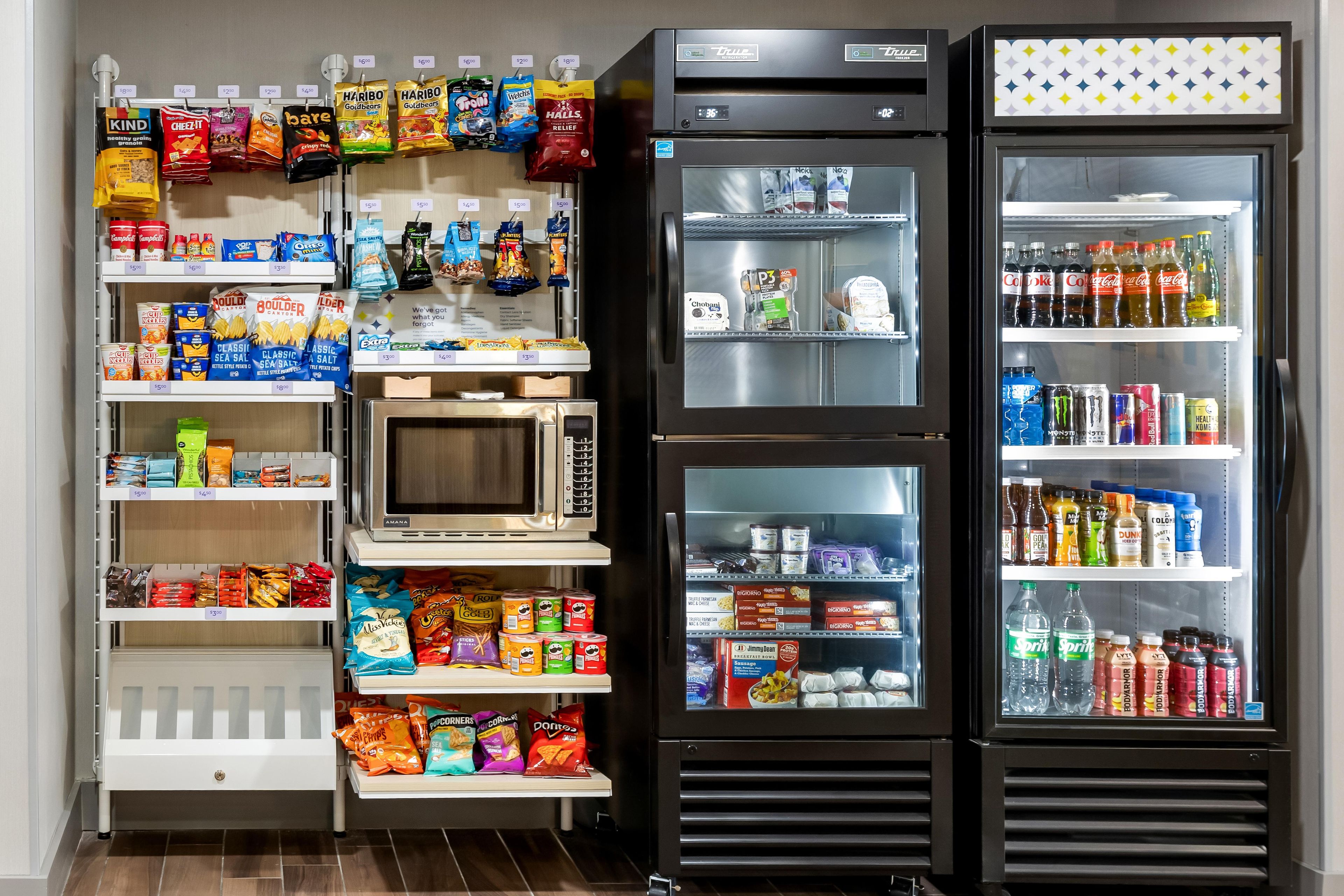 A self-service snack and beverage station with various snacks, drinks, and a microwave.