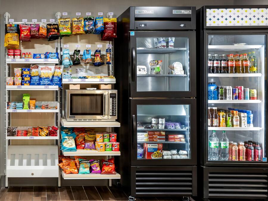 A self-service snack and beverage station with various snacks, drinks, and a microwave.