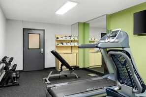 A gym with exercise equipment, a treadmill, and a wall-mounted TV. - Spark by Hilton Akron Fairlawn (Akron)