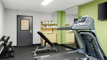 A gym with exercise equipment, a treadmill, and a wall-mounted TV.